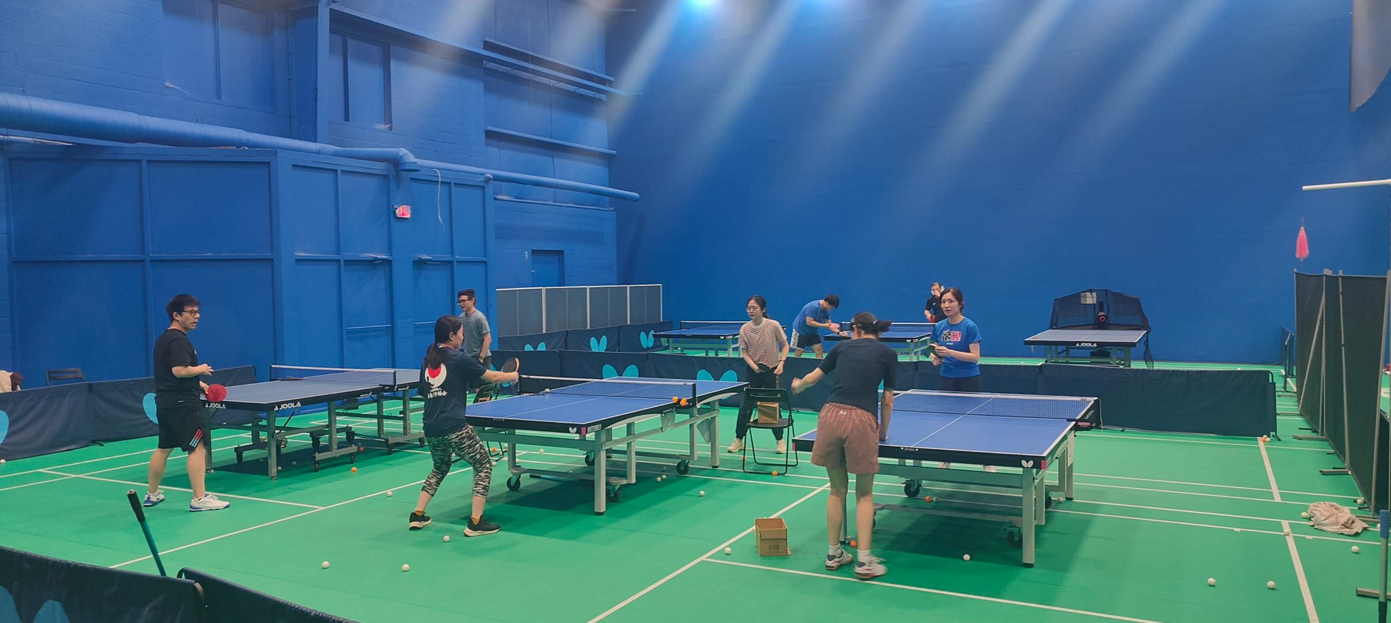 Players training at J&M Brothers — adults practicing at multiple tables during an open play session